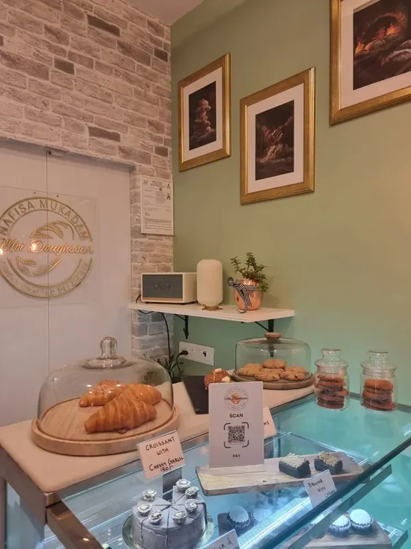 Moi Doughssier display counter with croissants under glass dome, cookies and gold-framed artwork